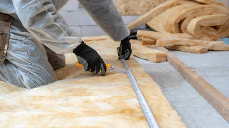 Person measuring and cutting a sheet of floor insulation in Norwalk, CT.