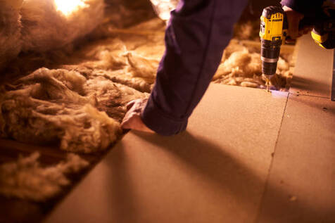 Person securing floor boards on top of insulation in a Norwalk basement.