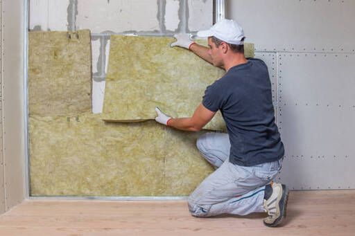 Person installing insulation panels into a wall.