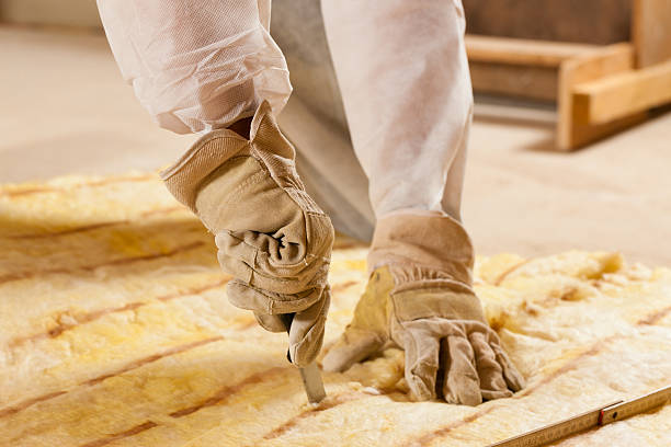 Person with protective glove cutting a sheet of insulation to size in Norwalk, CT.