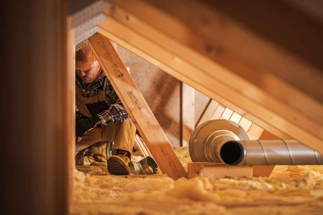 Person installing insulation in an unfinished attic floor in Norwalk, CT. 